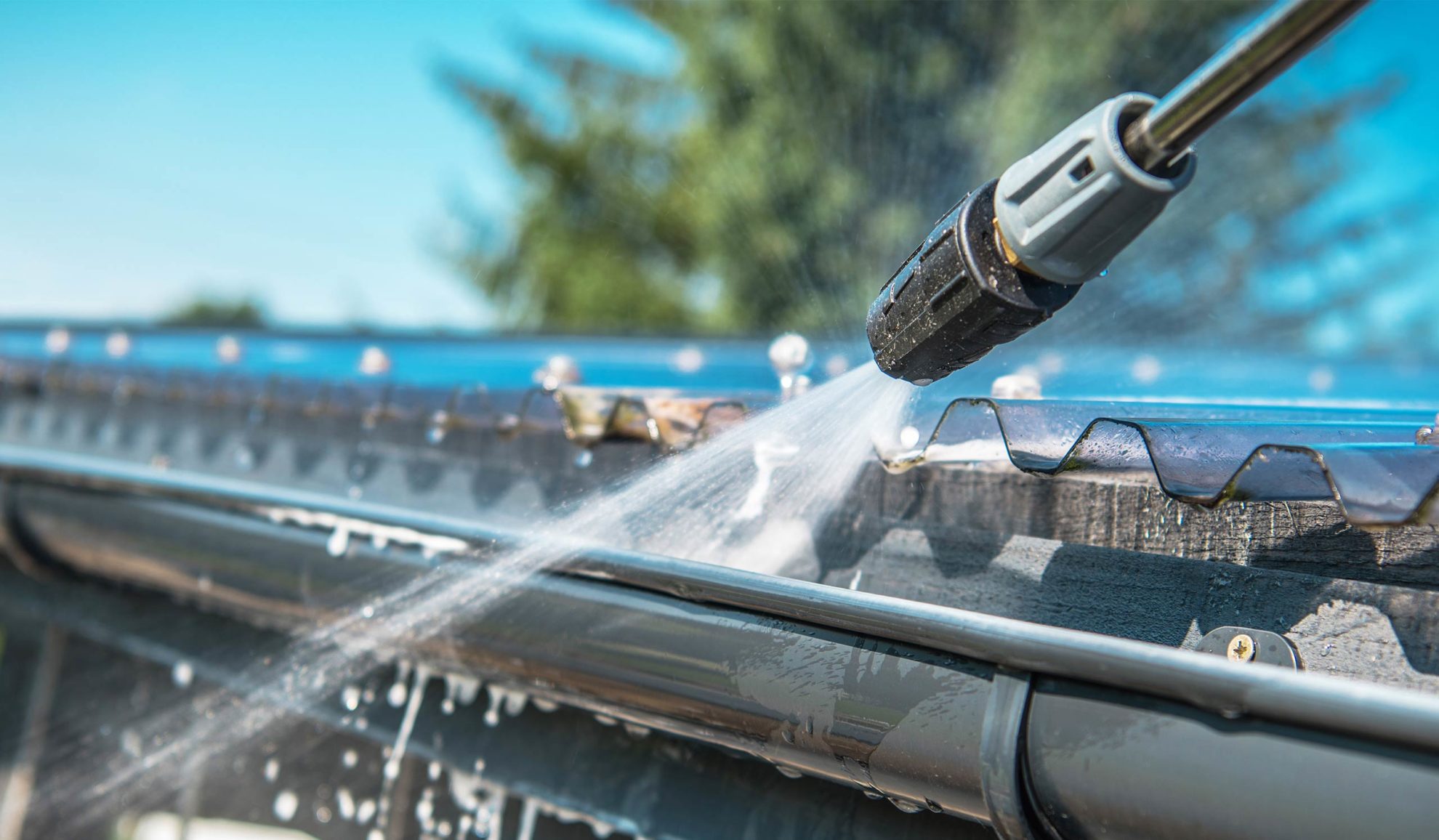 pressure washer close up cleaning aluminum gutter at house roof canton ms